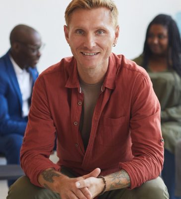 smiling-man-at-group-therapy-session-7HU8Q2C-pf2n5igpmfm4ppl9w5nt89pd7hae8a7fb8ryn904qo